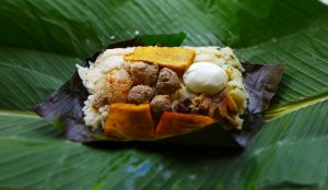 Fleisch, Gemüse, Reis und Kochbanane auf einem Bananenblatt