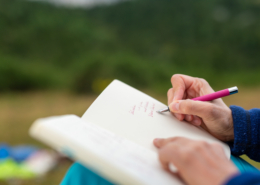 MIt der Hand schreibend in einem Heft.